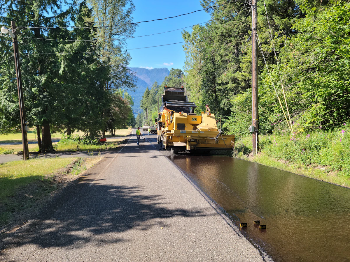 Road crew applying aggregate and pavement material during a road project.